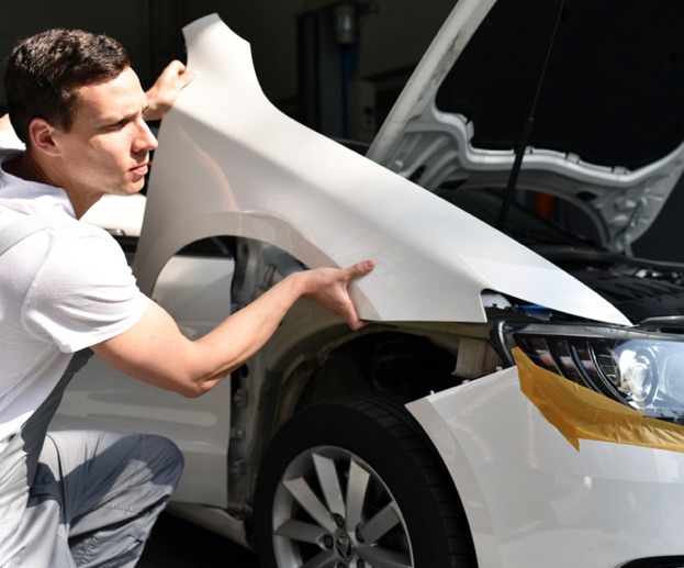 Mécanicien automobile installant une nouvelle aile blanche sur une voiture à Rambouillet dans les Yvelines 78