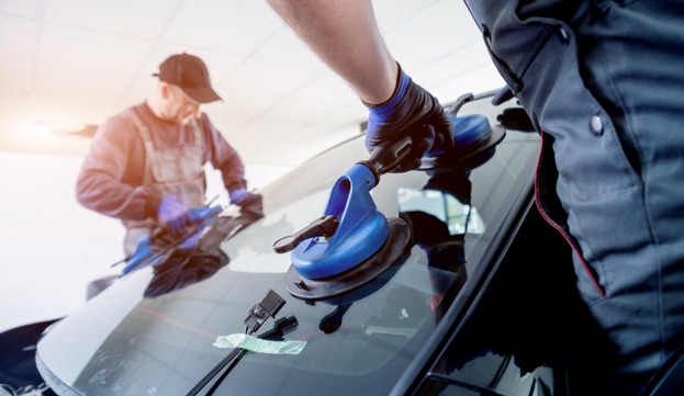 Deux techniciens automobiles remplacent le pare-brise d'une voiture avec des ventouses à Rambouillet dans les Yvelines 78